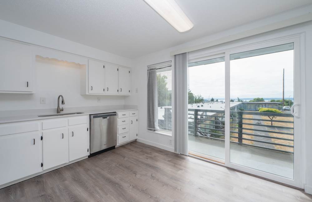 Open kitchen with modern appliances next to balcony at The Sage Collection in Tacoma, Washington