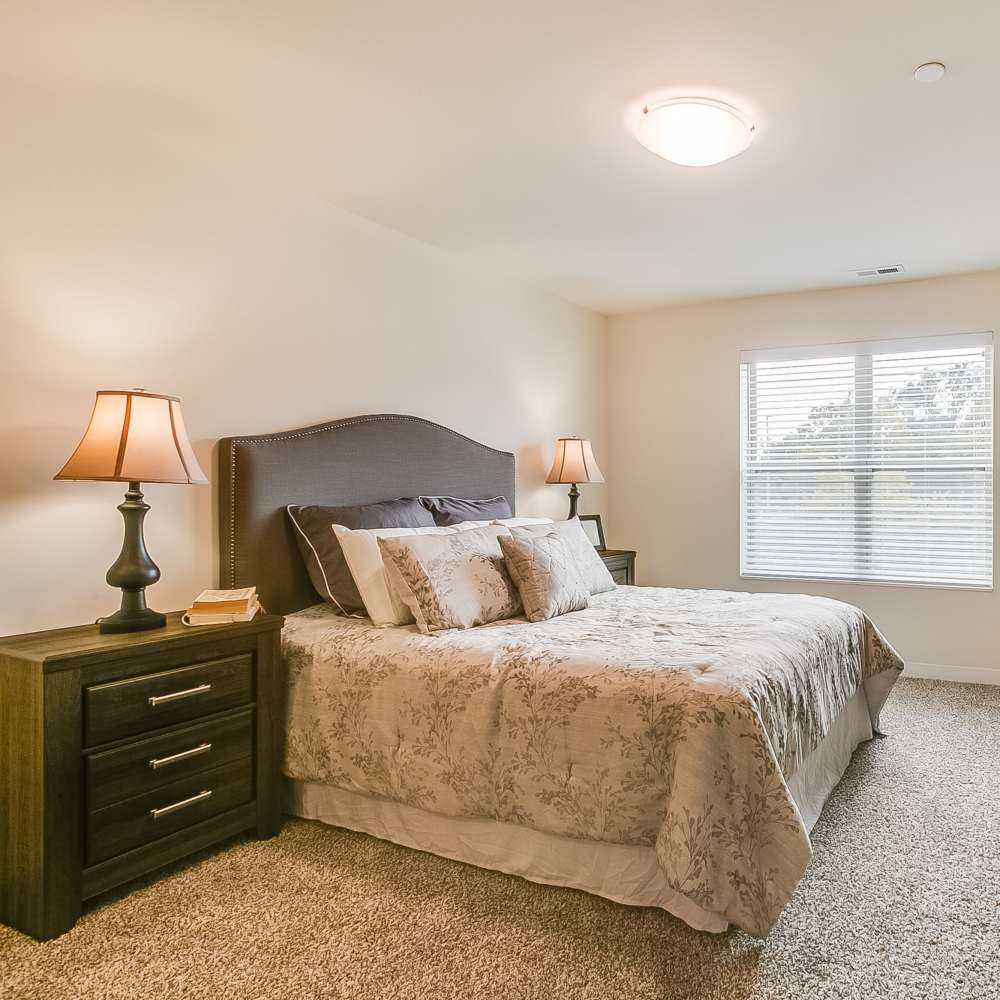 Cozy bedroom with large windows and lamps at Chelsea Commons in Sugar Grove Illinois