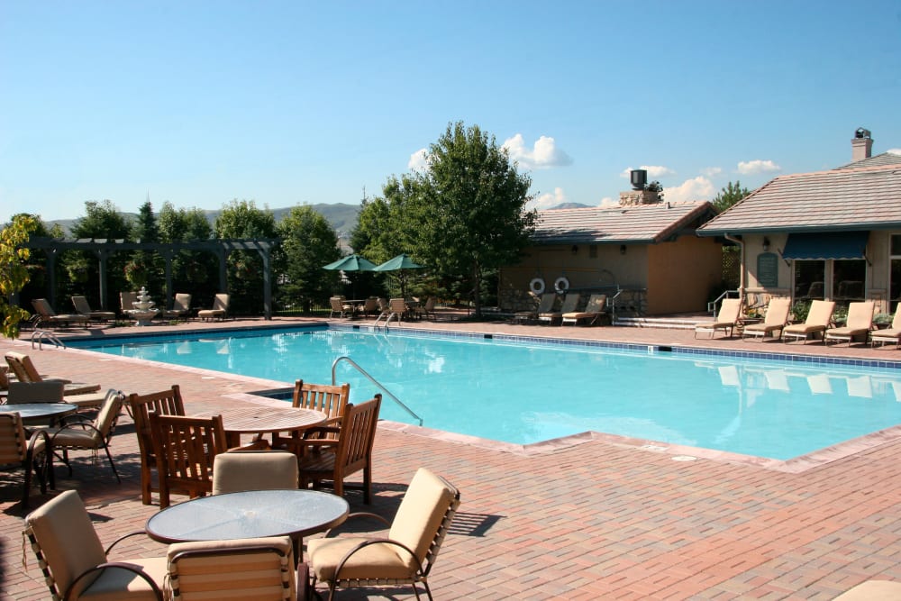 Sparkling swimming pool with poolside tables and lounge chairs at Montrachet Apartment Homes in Lakewood, Colorado