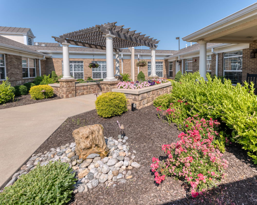 Courtyard with a beautiful flowers and paved walkway at Addington Place of Shoal Creek in Kansas City, Missouri