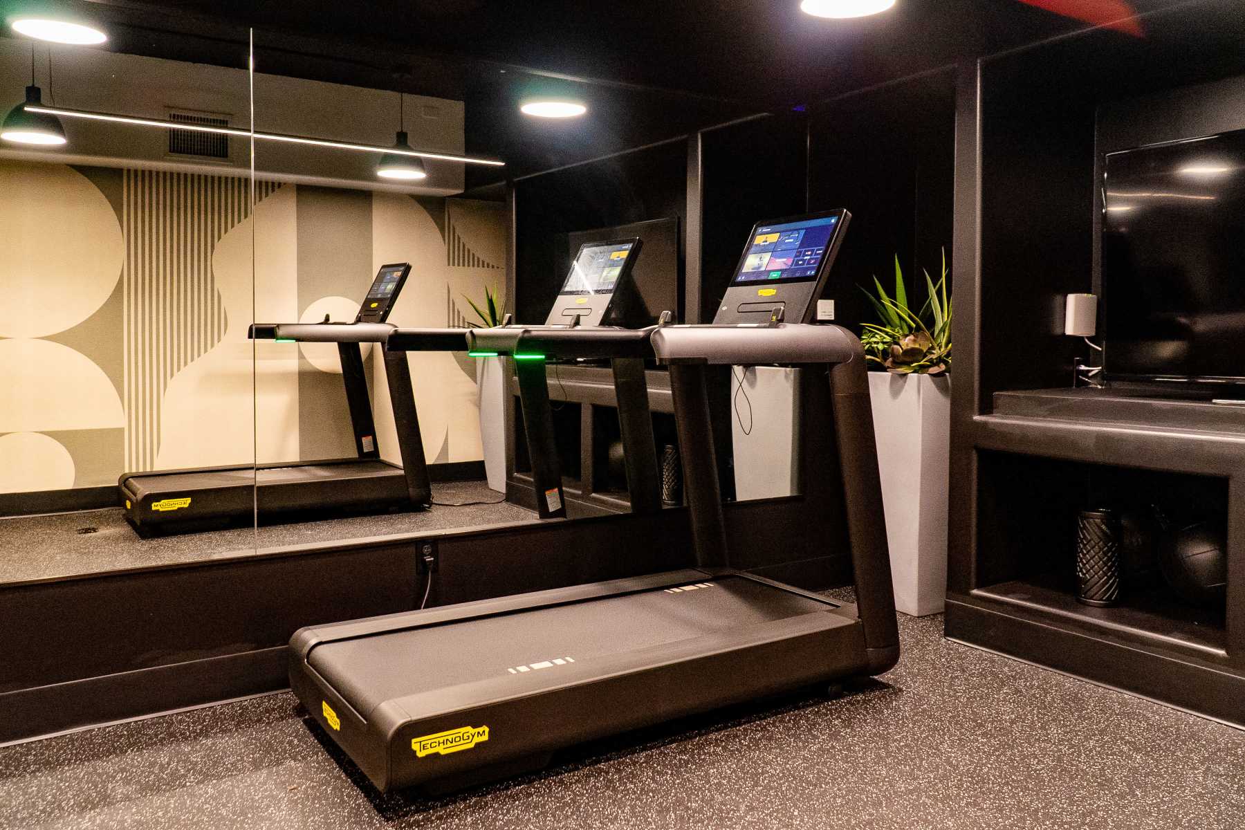 Modern gym with Technogym treadmills, mirror wall at Luxe Villas in Brentwood, California