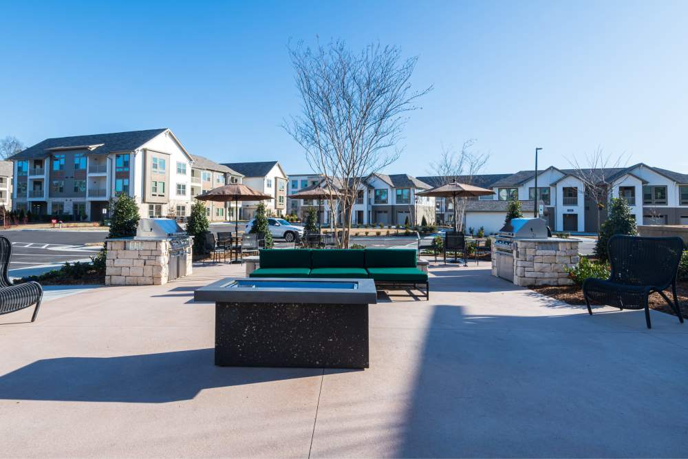 Outdoor patio area with seating arrangements and fire pit surrounded by apartment buildings at The Reserve at Patterson Place in Durham, North Carolina