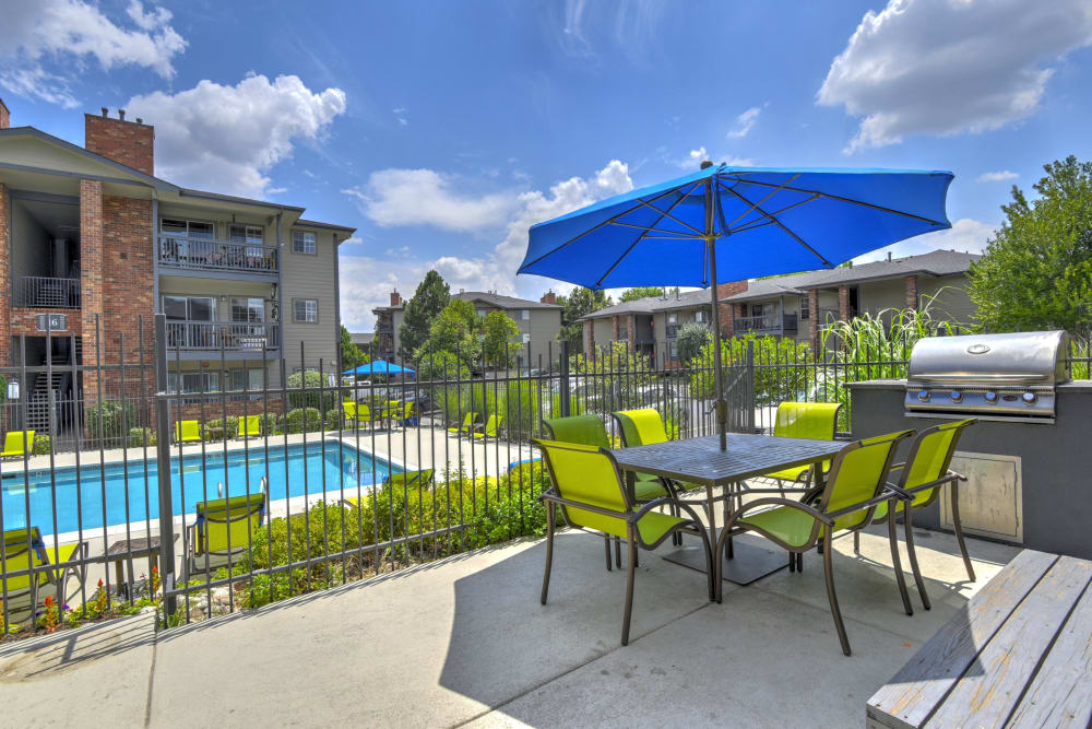 Poolside patio with a covered table and a barbecue at Arapahoe Club Apartments in Denver, Colorado