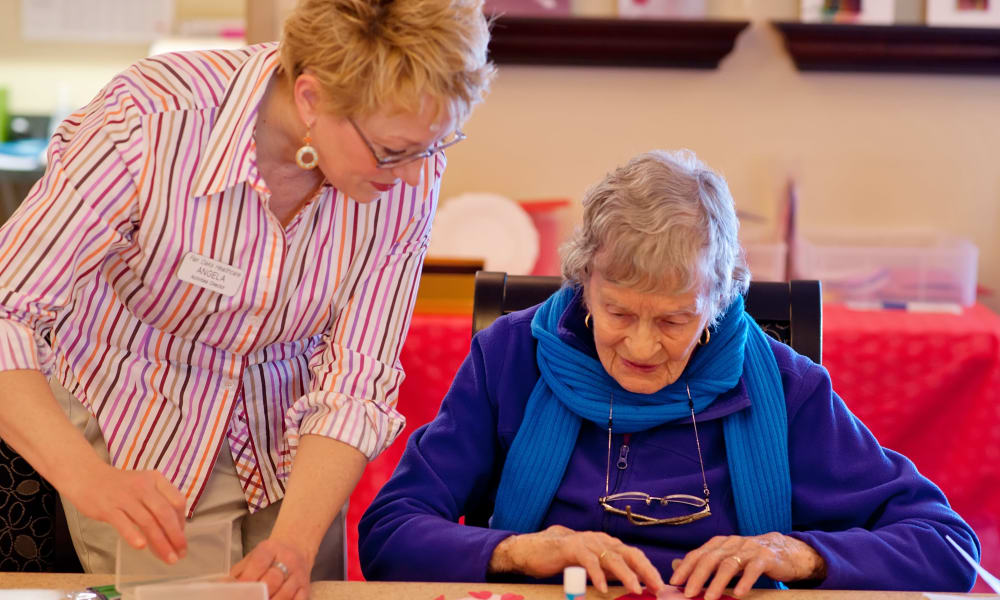 Caretaker helping a resident with arts and crafts at Fair Oaks Health Care Center in Crystal Lake, Illinois