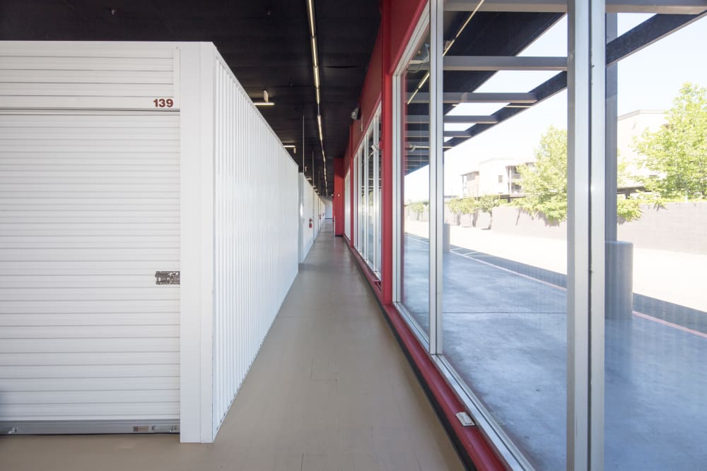 A Hallway of storage units, with large windows on the right.