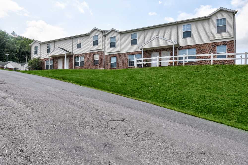Two-story apartment building with green lawn and white fence, inviting entrance and clear blue sky at Catawba Club in Berkeley Springs, West Virginia