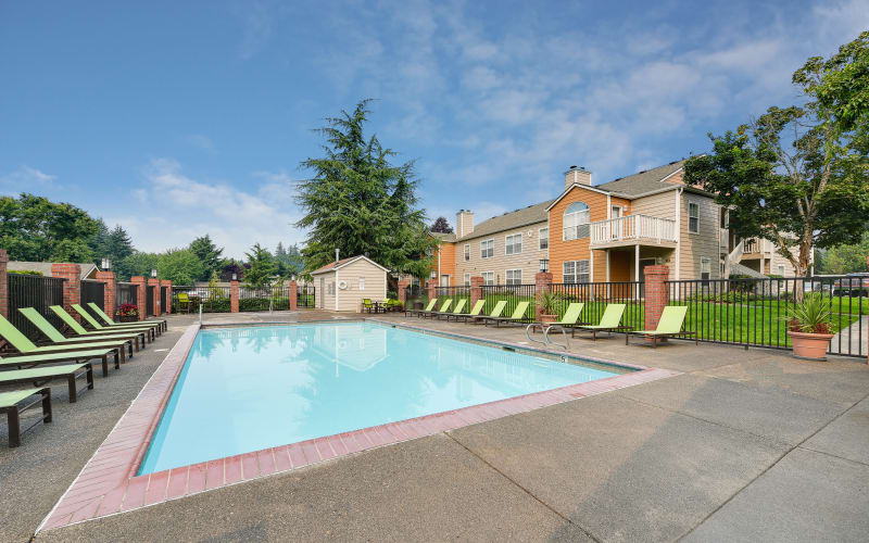 Lounge chairs by the welcoming blue pool on a sunny day at Carriage Park Apartments in Vancouver, Washington