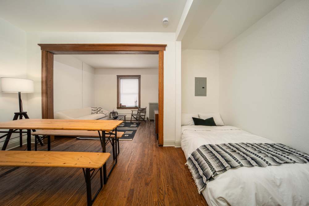 Open layout living room and connecting dining room with hard-wood style flooring and plenty of room for a couch and more at Detroit Living in Detroit, Michigan
