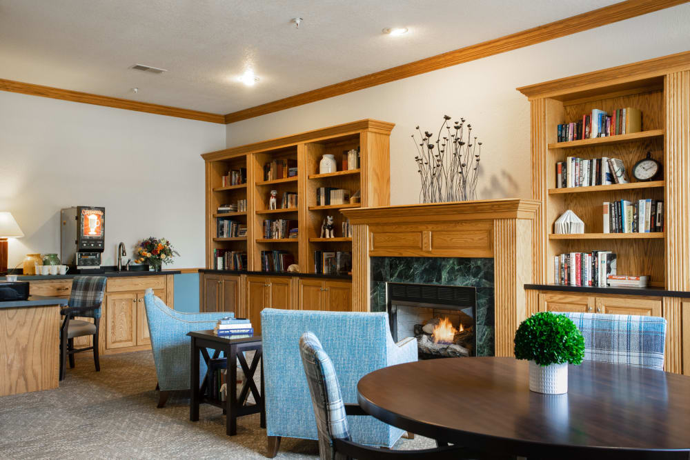 Lounge with a fireplace and several shelves of books at Randall Residence of Decatur in Decatur, Illinois