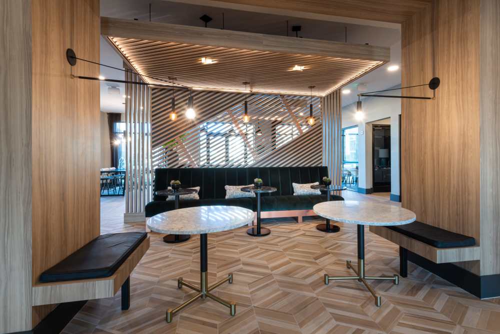 Modern lounge area featuring marble tables, black cushioned benches along the walls under stylish lighting fixtures within an open space design concept at The Reserve at Patterson Place in Durham, North Carolina