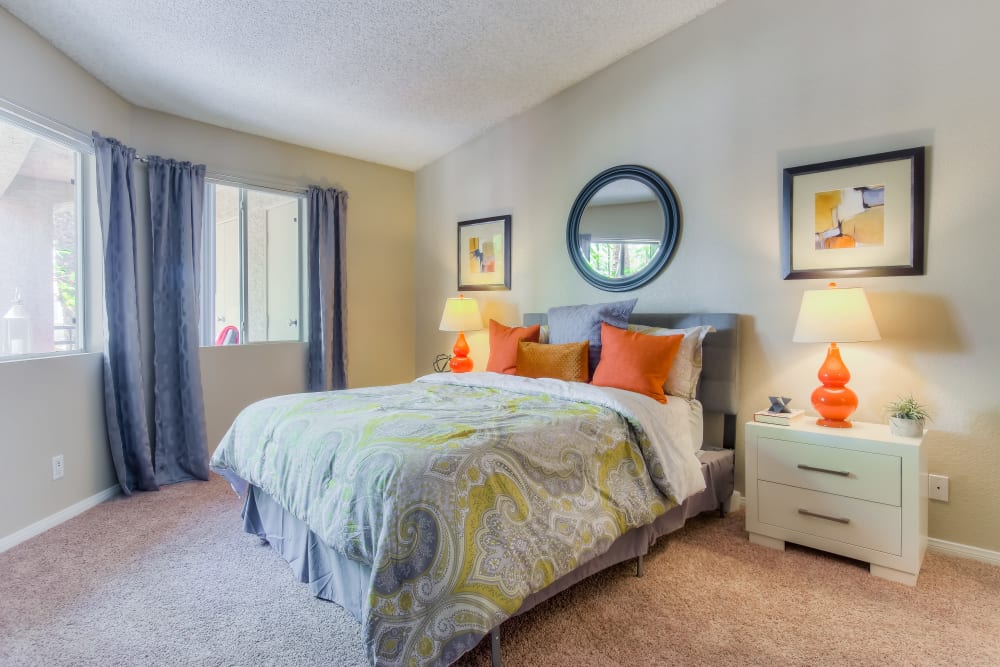 Decorated master bedroom with large windows at Tuscany Village Apartments in Ontario, California