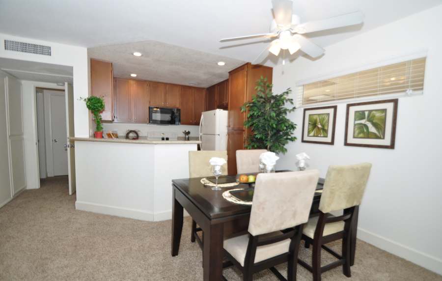Charming dining area adorned with elegant decor, seamlessly connected to a modern kitchen featuring rich cabinetry at River Run Village in San Diego, California