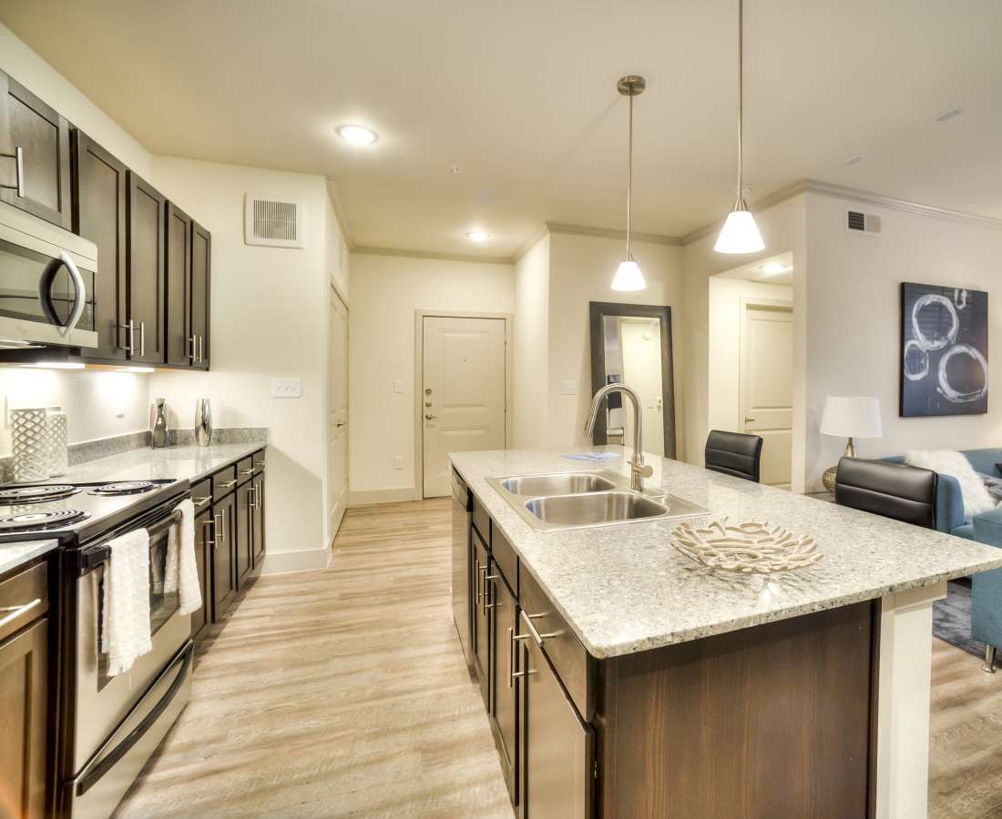 Modern kitchen with granite countertops, stainless steel appliances, island, and wood-style flooring at Magnolia Park Apartments in Houston, Texas