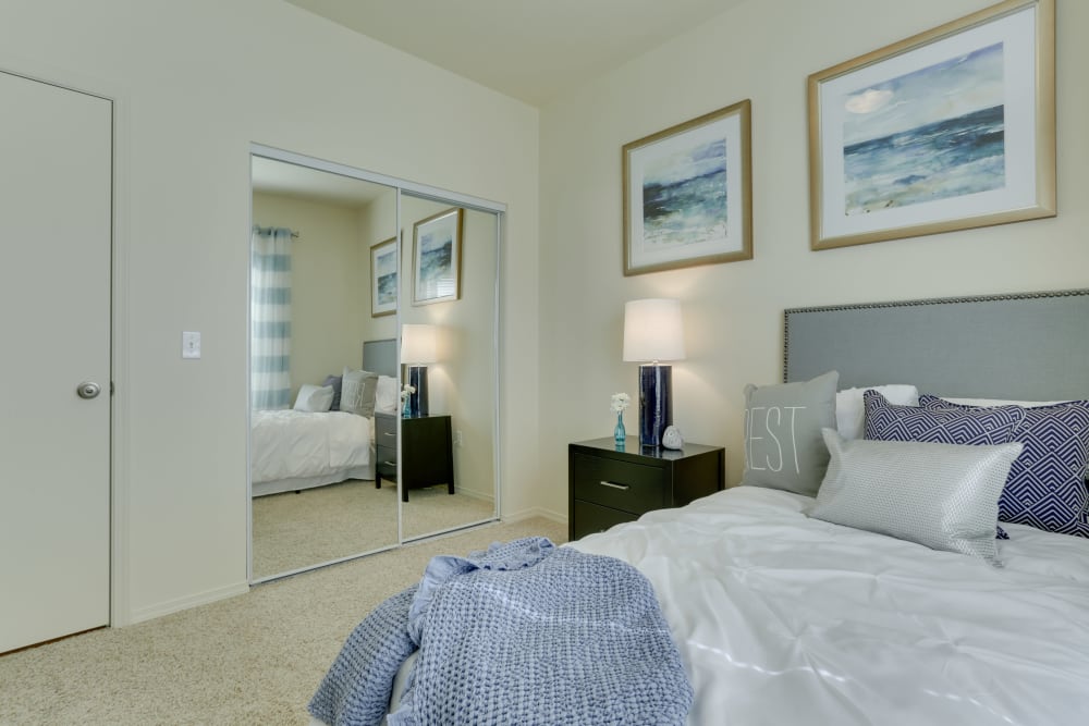 Master bedroom with a large mirrored closet door at The Landings at Morrison Apartments in Gresham, Oregon