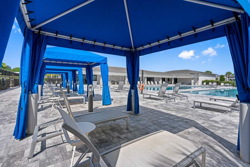 Resort-style pool area with cabanas and lounge chairs under blue skies at Solera at Avalon Trails in Delray Beach, Florida