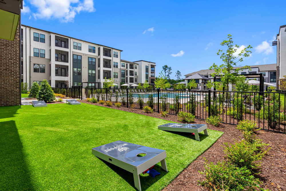 Gaming lawn with cornhole games, string lights, and maintained landscaping at Westport Lofts in Belville, North Carolina