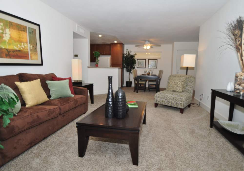 Inviting living room featuring a plush brown sofa and an open layout leading to a contemporary kitchen atRiver Run Village in San Diego, California