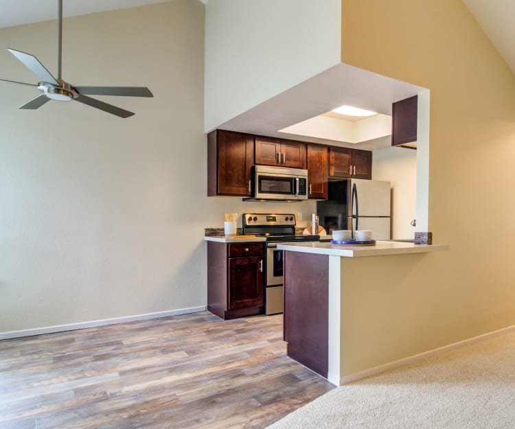 Dining area with a vaulted ceiling and a ceiling fan next to the modern kitchen in a model home at Sofi Lake Oswego in Lake Oswego, Oregon