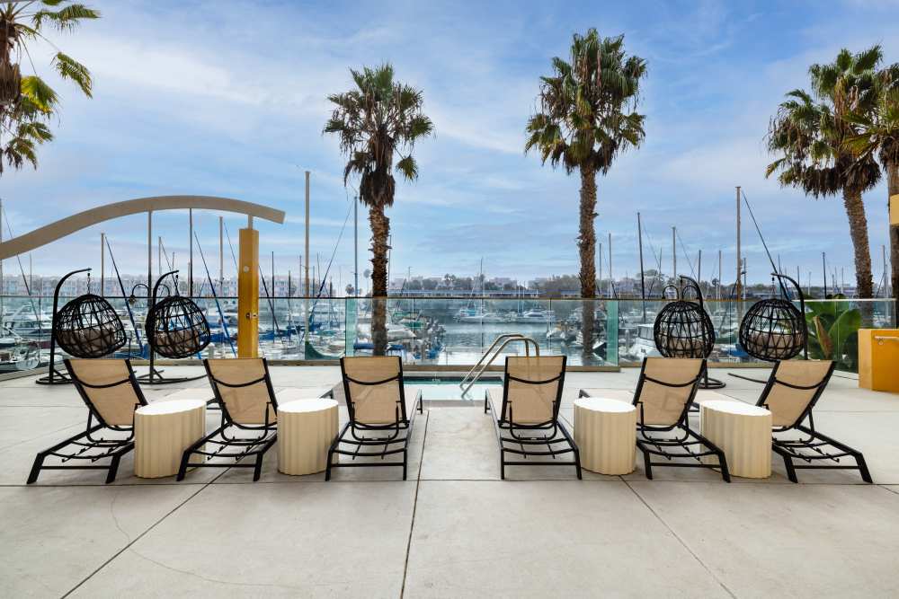 Luxury chairs positioned by a pool overlooking boats at Capri Apartments in Marina Del Rey, California