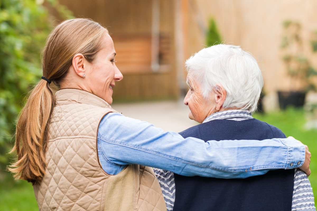 Young adult walking with senior outdoors at Keystone Place at Newbury Brook in Torrington, Connecticut
