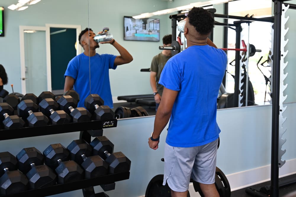 A resident drinking from a water bottle in the fitness center at The Waters at Millerville in Baton Rouge, Louisiana