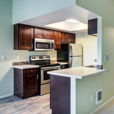 Modern kitchen with granite countertops and a breakfast bar in a model home at Sofi Lake Oswego in Lake Oswego, Oregon