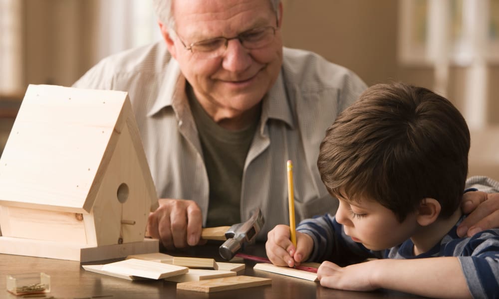 A resident and a boy building a birdhouse at Amaran Senior Living in Albuquerque, New Mexico.
