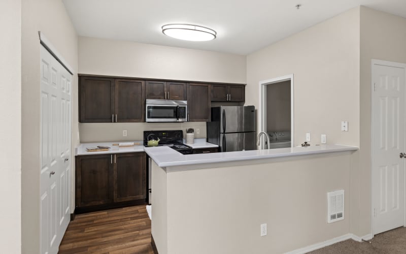 Renovated kitchen with a breakfast bar, stainless steel appliances and brown cabinets at Wildreed Apartments in Everett, Washington