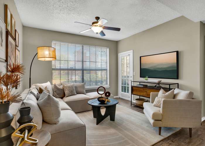 Living room with ceiling fan and large window at Carrollton Park of North Dallas in Dallas, Texas