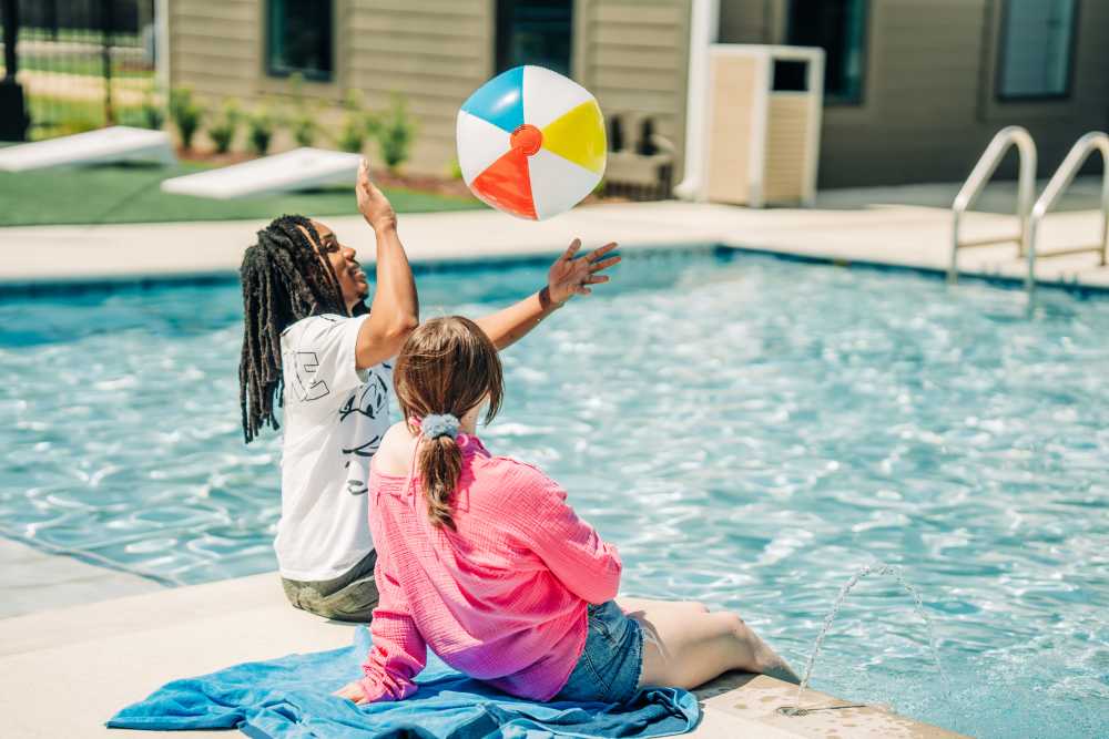 Residents relaxing on the edge of a pool at The Waters at Promenade in Marrero, Louisiana
