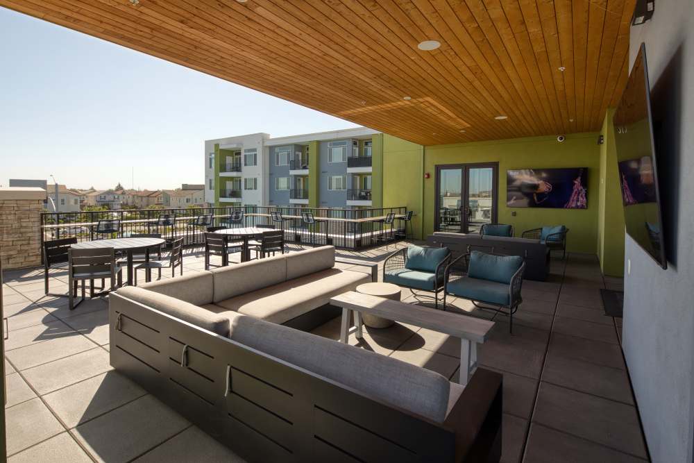 Outdoor lounge area with seating and flat screen television at Zeta Luxury Apartments in Sacramento, California