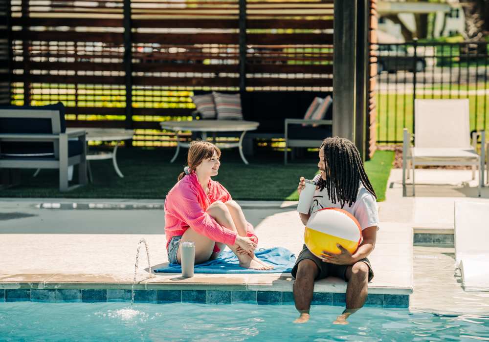 Residents sitting on the edge of a swimming pool at The Waters at Promenade in Marrero, Louisiana