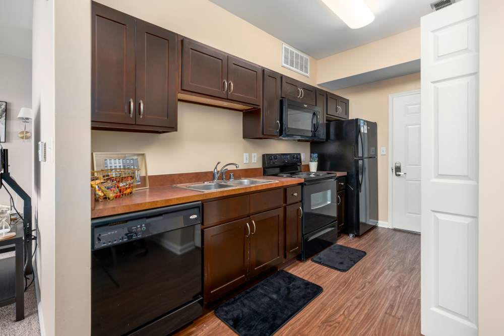 Kitchen with black appliances and wooden flooring at Mazza Grandmarc in College Park, Maryland