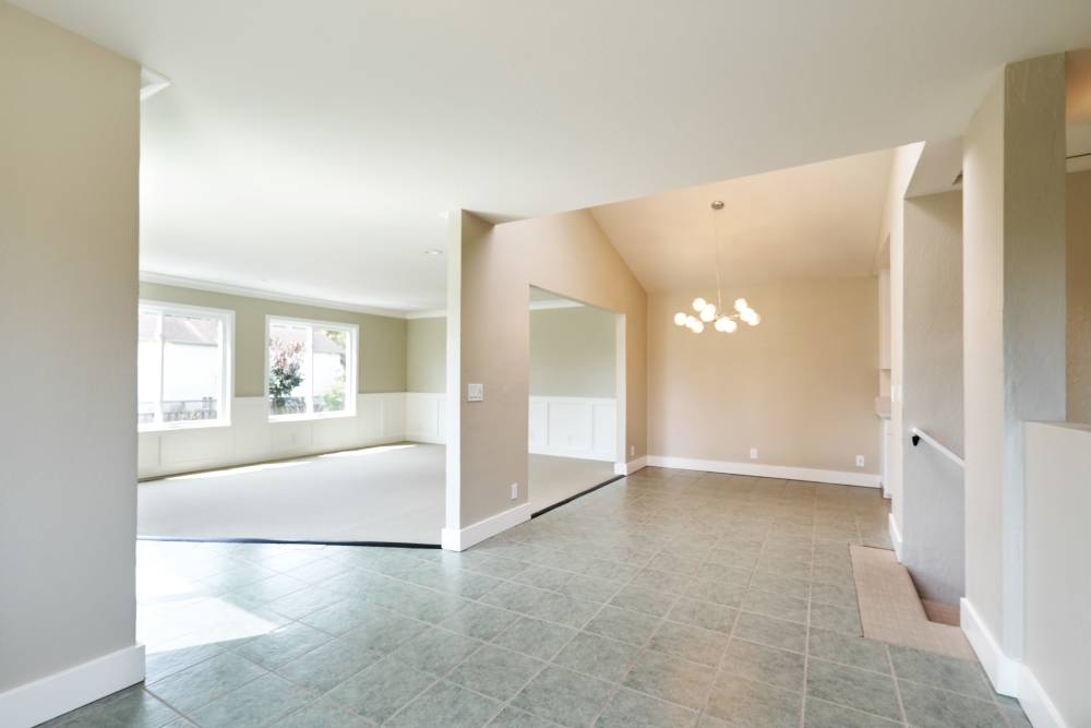 Bright, empty room with tiled flooring, light-colored walls, and large windows allowing natural light, featuring an open layout.at Santa Cruz Coast Homes in Santa Cruz, California