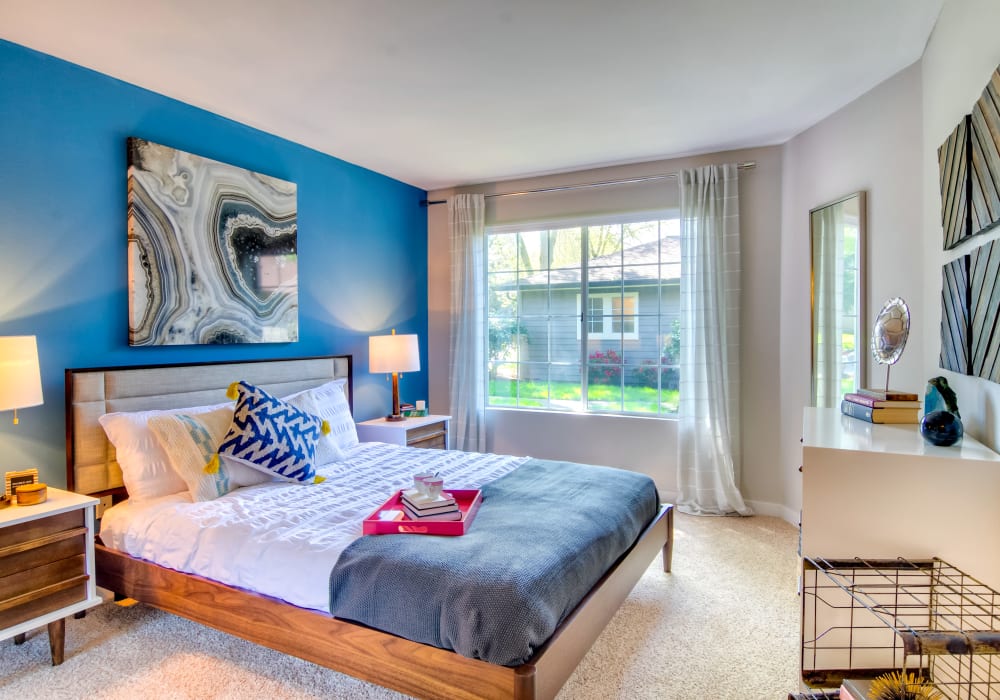 Well-furnished bedroom with an accent wall and draped windows in a model home at Sofi at Murrayhill in Beaverton, Oregon