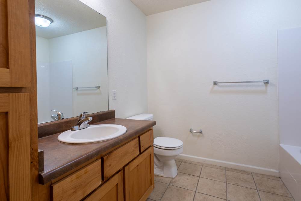 Charming bathroom retreat with modern fixtures and warm wooden cabinetry at Adobe Ranch in Borger, Texas.