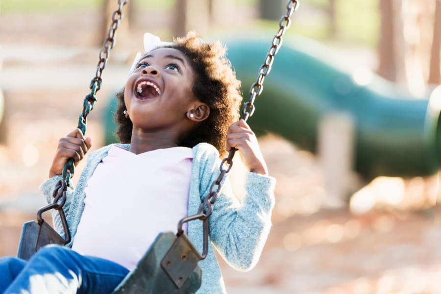 Resident child playing on the swings at the playground at Overlook Manor Townhomes in Frederick, Maryland