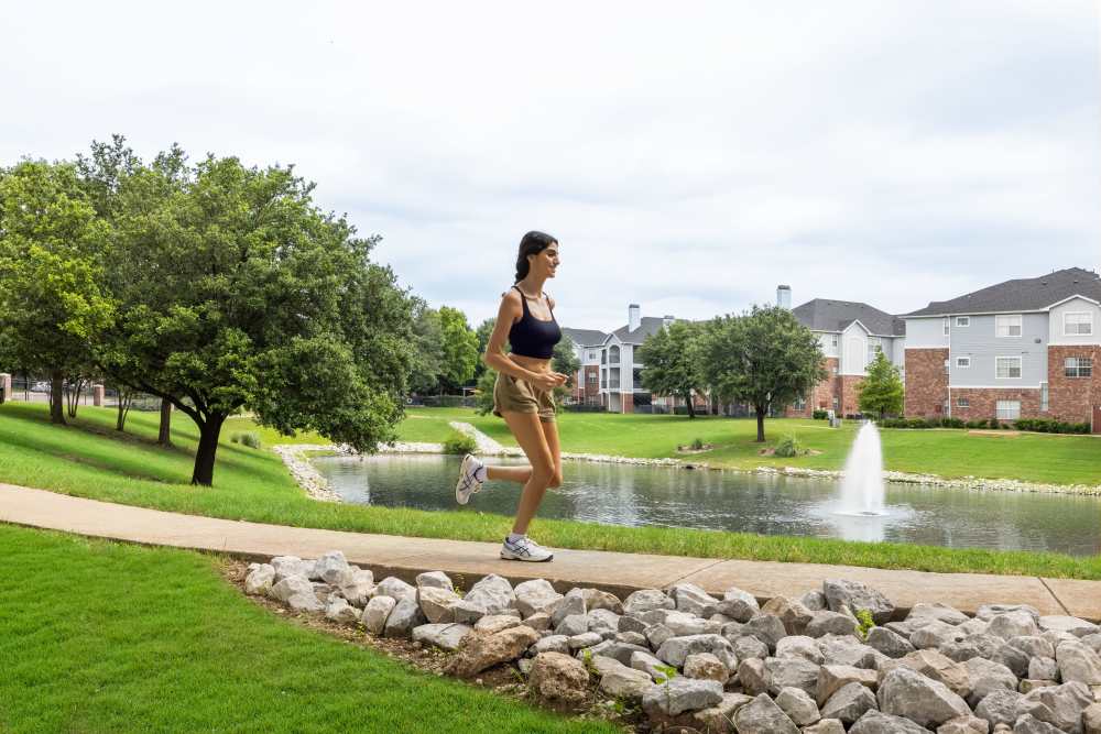 Person running by pond on ground Breckinridge Point Apartments in Richardson, TX