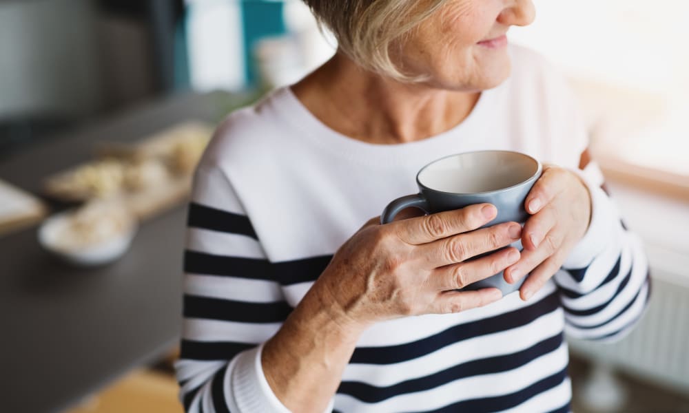 An elderly woman drinking coffee at Brightwater Senior Living of Capital Crossing in Regina, Saskatchewan