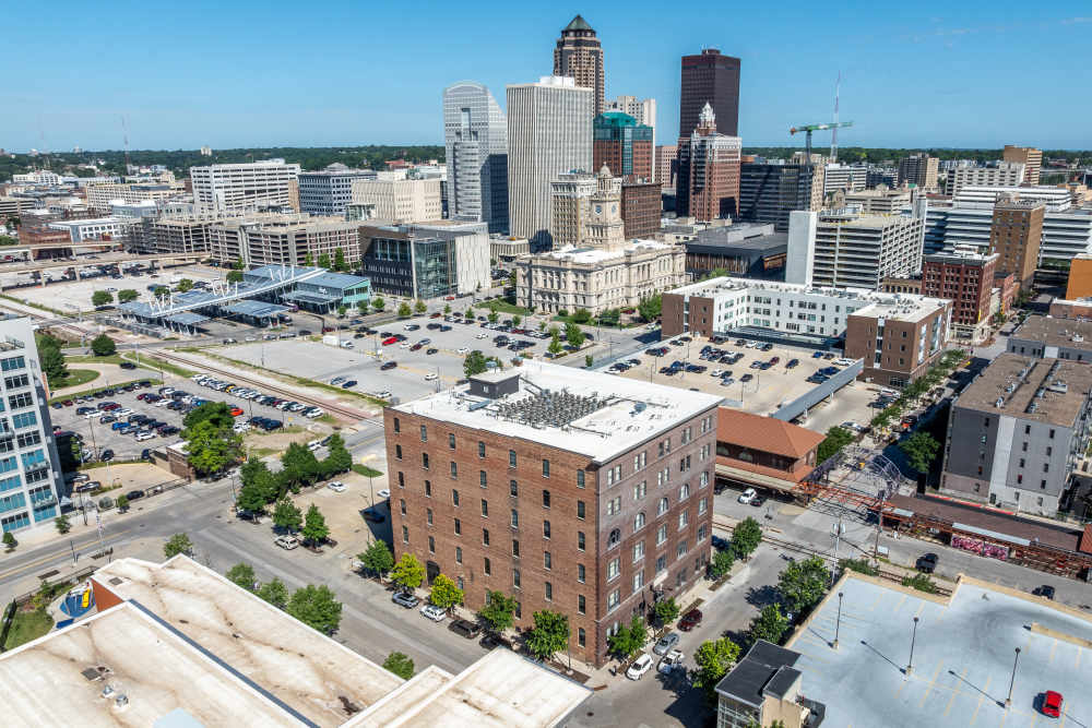 Modern apartment community with vibrant city skyline, featuring landscaped grounds and convenient parking options at Rumely Lofts in Des Moines, Iowa