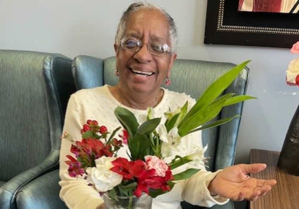 Resident smiling with flowers at Truewood by Merrill, Keller in Keller, Texas