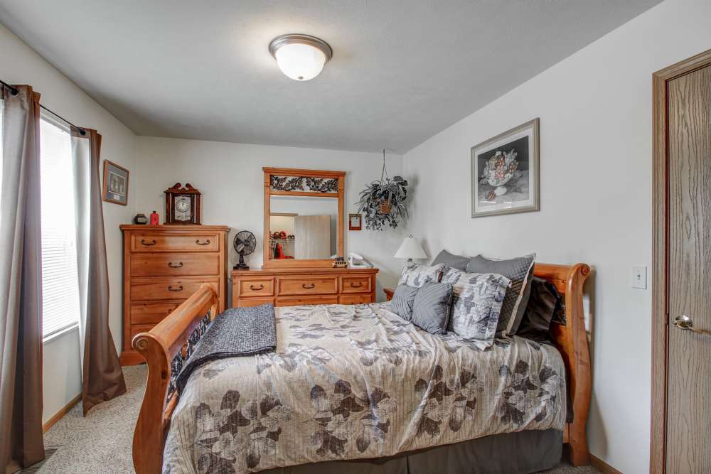 Cozy bedroom with wooden furniture, floral bedding, and natural light from windows at Hallet Crossing in Michigan Center, Michigan