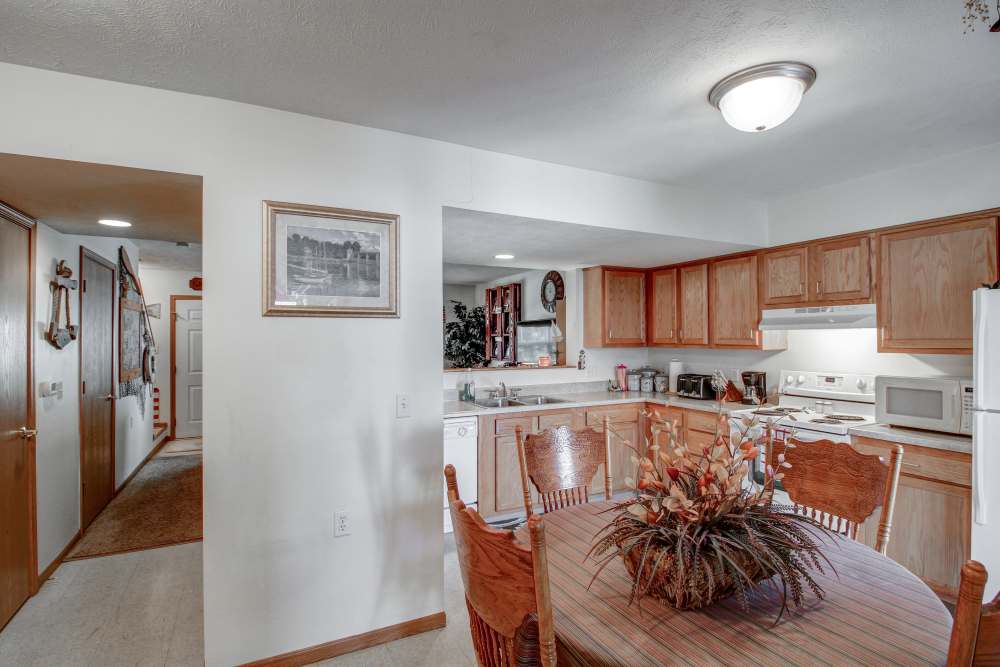 Bright kitchen with wooden cabinets, stainless steel appliances, and a dining area featuring a floral centerpiece at Hallet Crossing in Michigan Center, Michigan