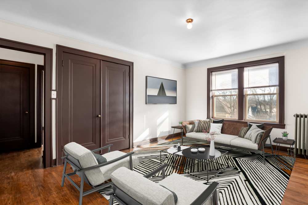 Open layout living room and connecting dining room with hard-wood style flooring and plenty of room for a couch and more at Detroit Living in Detroit, Michigan