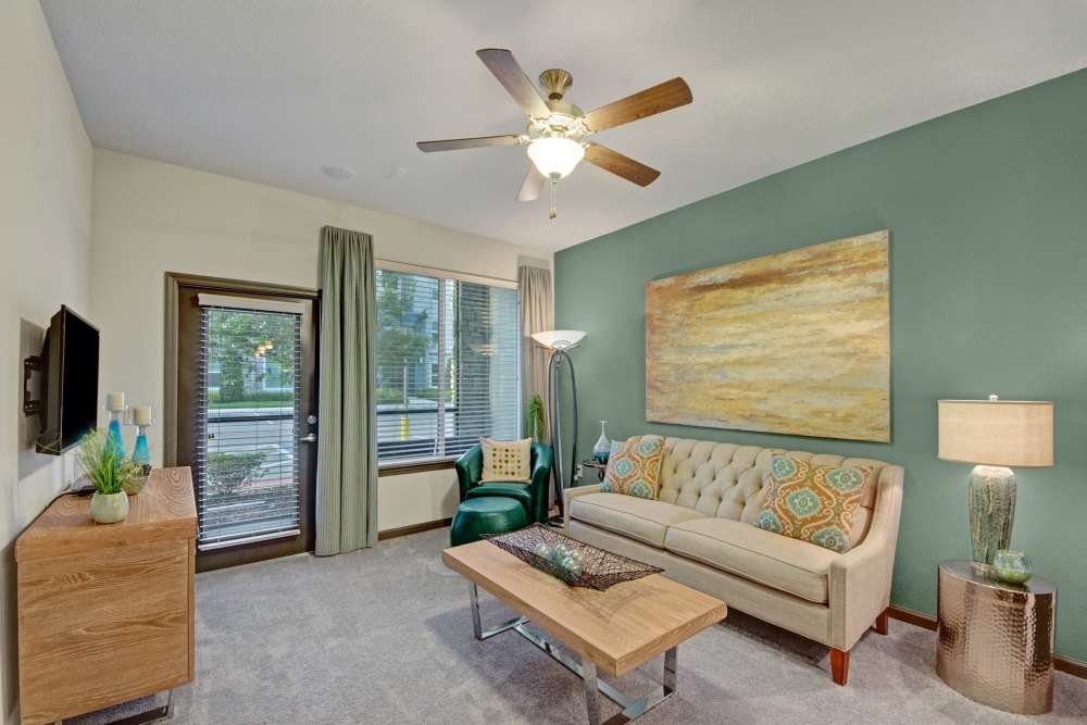 Living room with cpouch, chair, coffee table, ceiling fan and large window at The Courtney at Lake Shadow in Orlando, Florida 