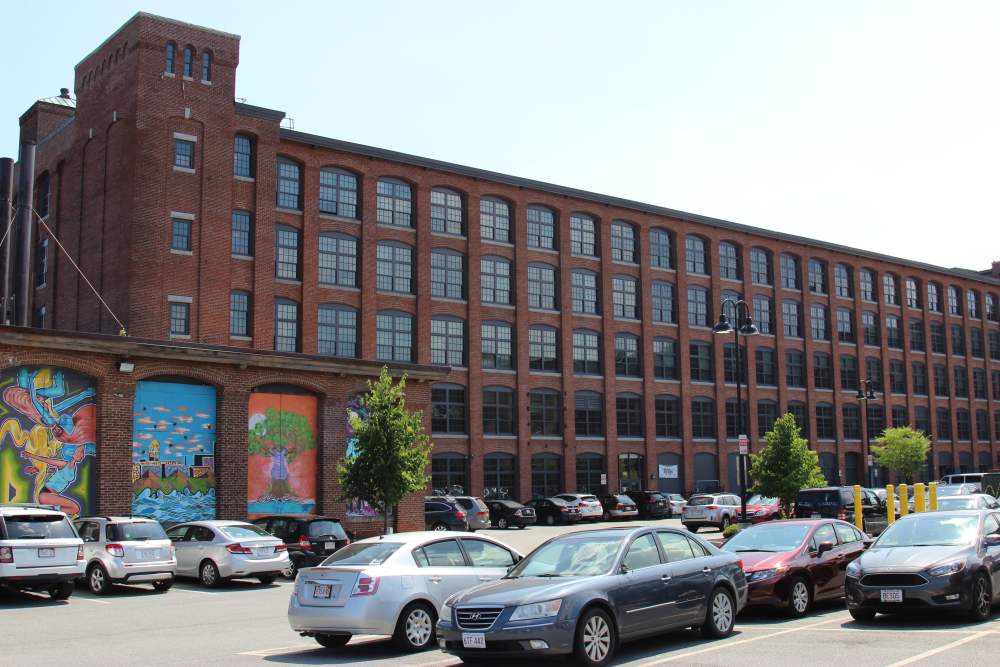 Community apartment with car parked at Union Crossing in Lawrence, Massachusetts