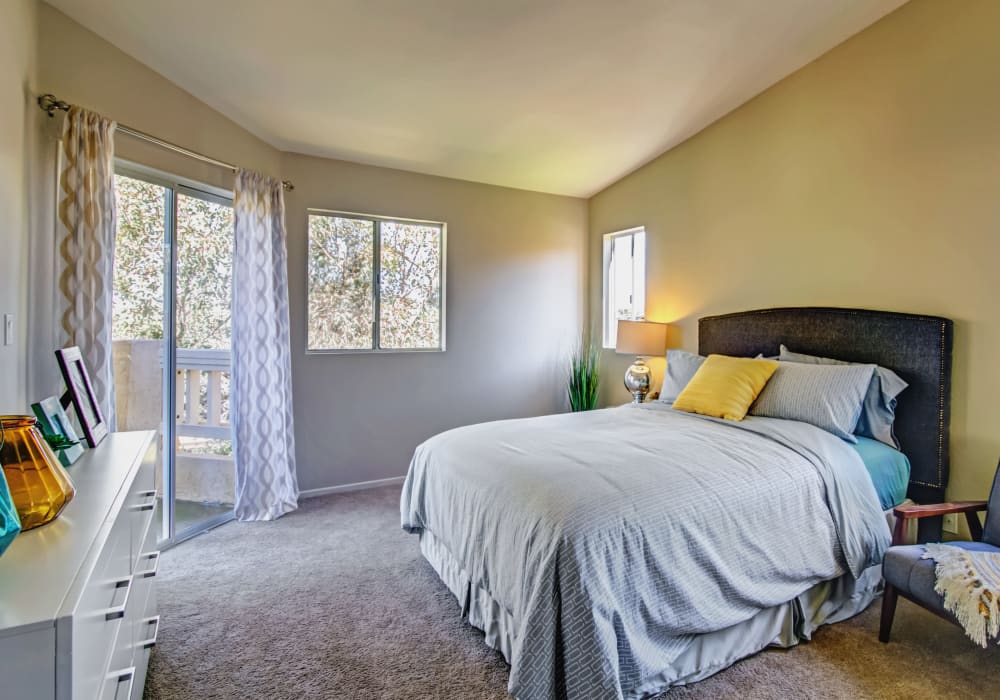 Master bedroom with sliding glass doors to the private balcony outside a model home at Sofi Canyon Hills in San Diego, California