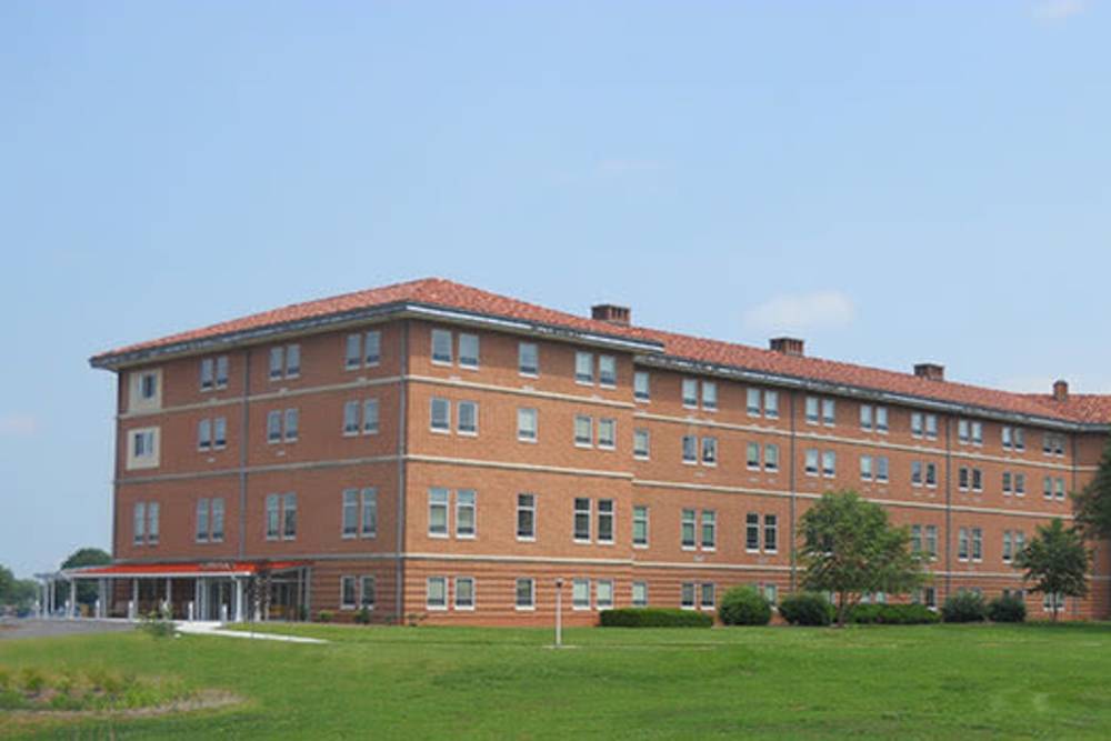 Brick apartment building with landscaped grounds and trees, sunny blue sky in background at Seton Village Apartments in Emmitsburg, Maryland