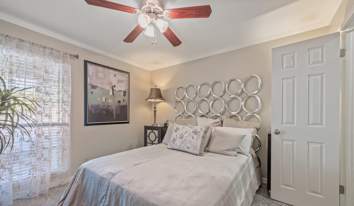 Bright bedroom with a comfortable bed, ceiling fan and a large window at The Willows in Shreveport, LA