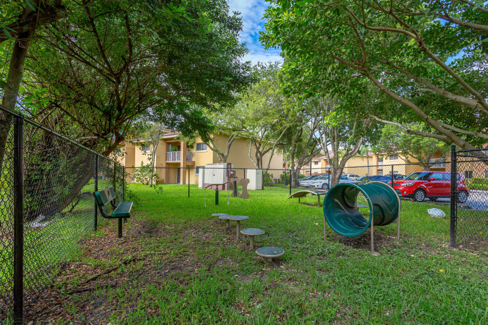 Fenced bark park at Fairway View Apartments with obstacles for dogs to play on.